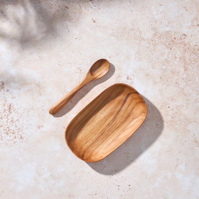 Palinopsia teak wooden plate and spoon on a textured beige surface
