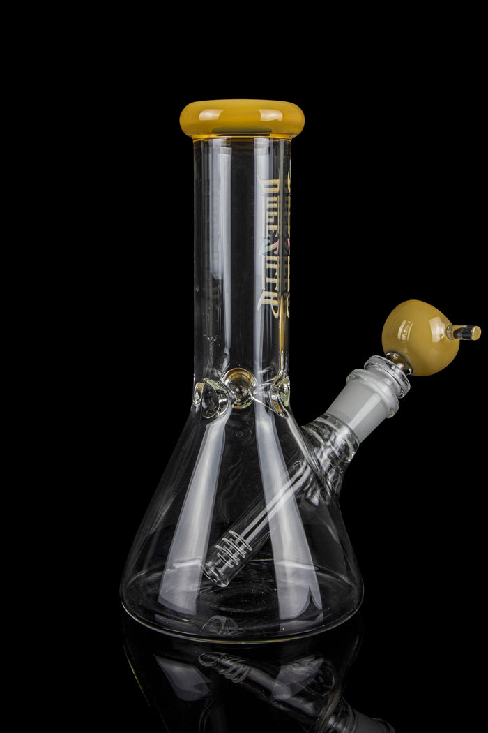 Clear glass bong with a yellow mouthpiece and downstem, reflecting on a dark surface.
