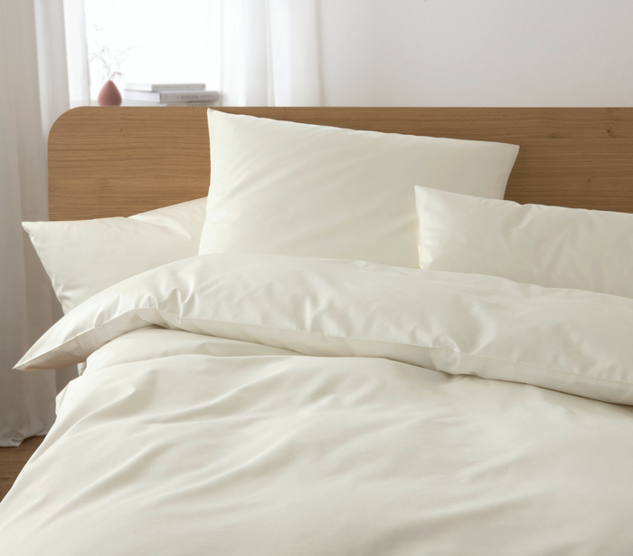 Beige bedding set on a bed with a wooden headboard.