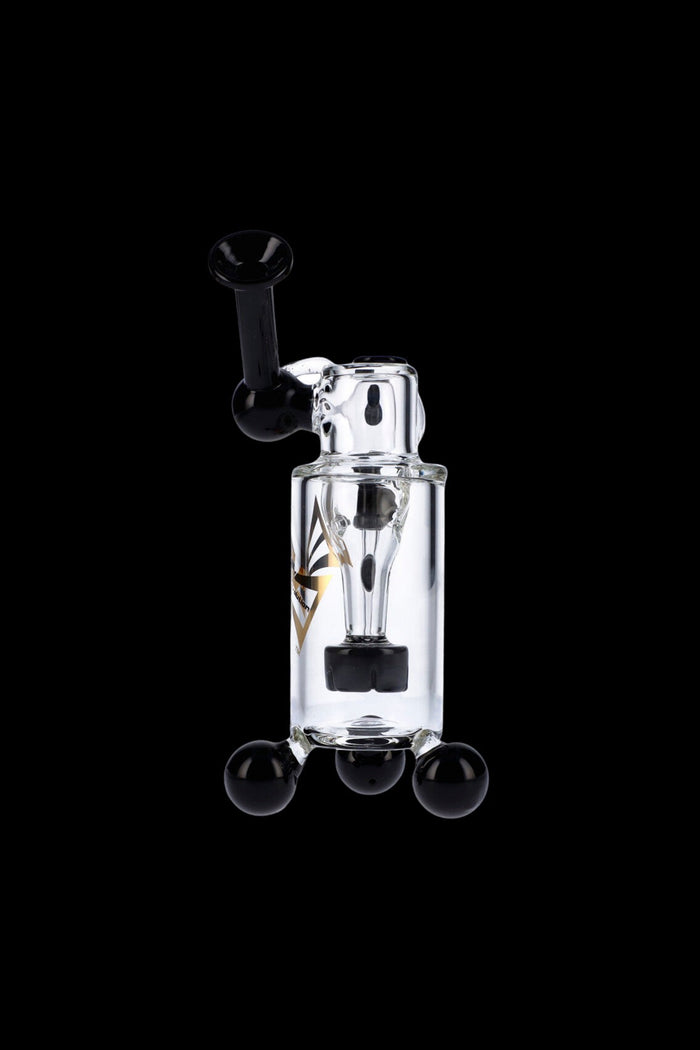 Clear glass dab rig with black accents and three spherical feet, isolated on a black background.