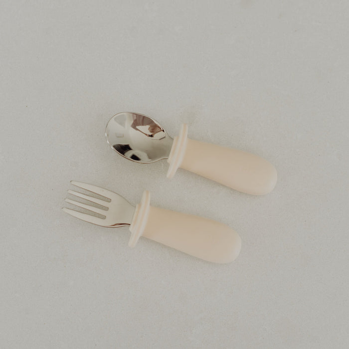 Set of children's cutlery with a fork and spoon on a light gray background