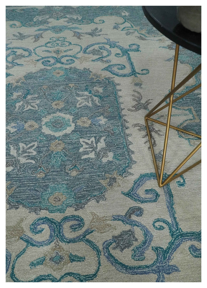 Ivory and blue hand-tufted wool rug close-up beside metal table leg and chair base