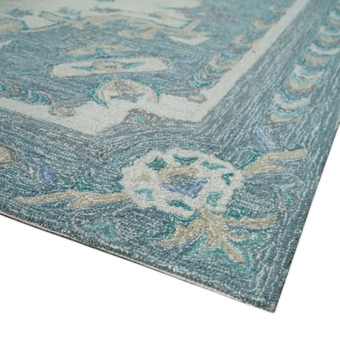Corner view of ivory and blue hand-tufted wool rug with floral scrolling ornament