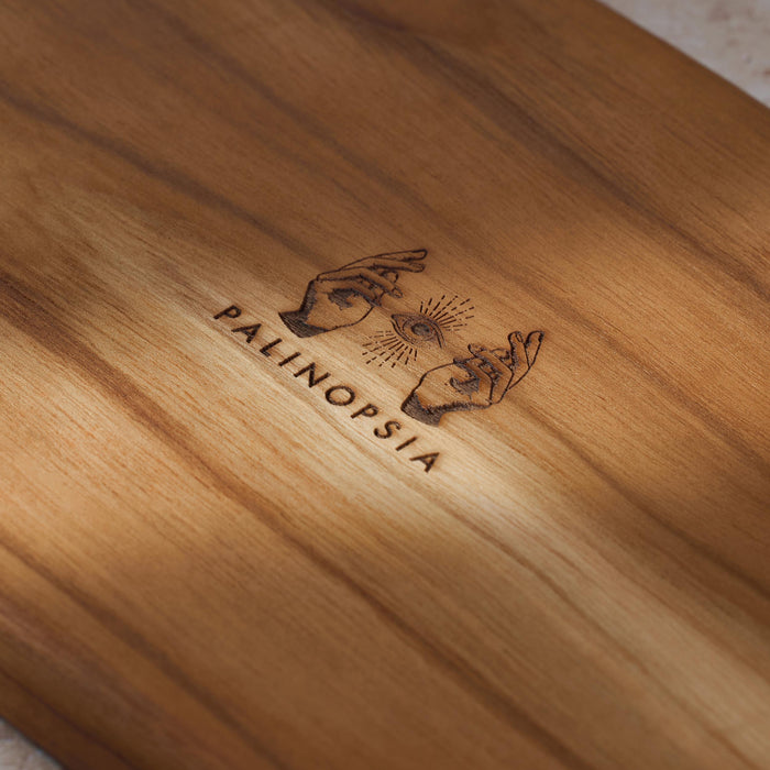 Detailed shot of a teak wooden serving platter with the Palinopsia logo on the bottom.
