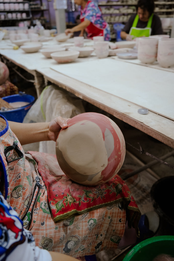 Ceramist polishes and cleans a ceramic bowl after shaping in a ceramics studio