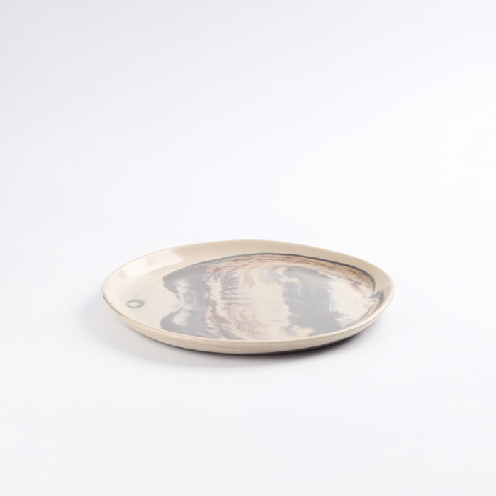 Round ceramic plate with a four colour marbled clay pattern on a white background by Palinopsia