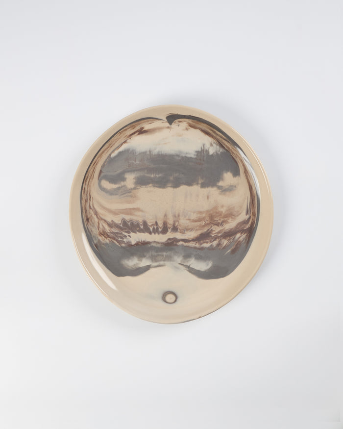 Round ceramic plate with a four colour marbled clay pattern on a white background by Palinopsia