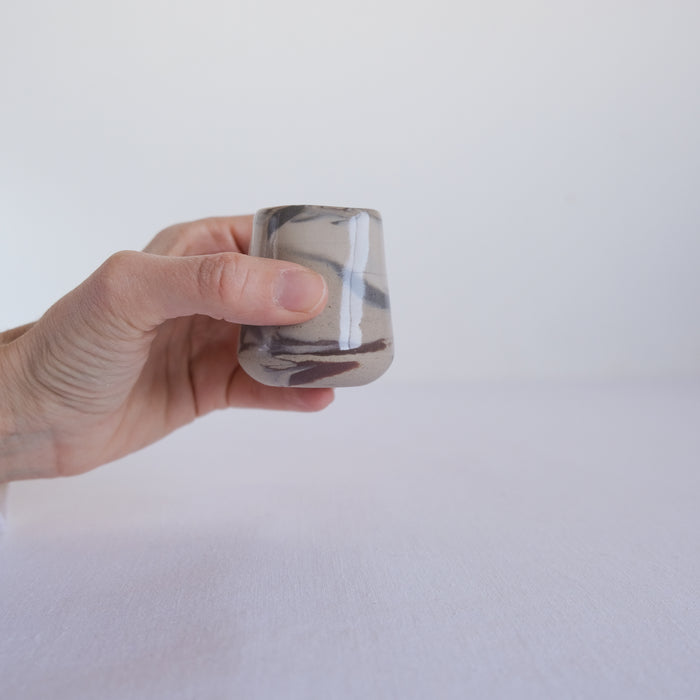 Hand holding a small marbled jus pitcher with abstract marble design
