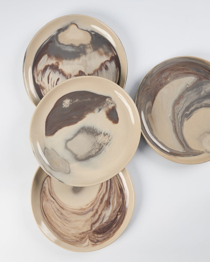 Set of four ceramic plates with marbled design on a white background