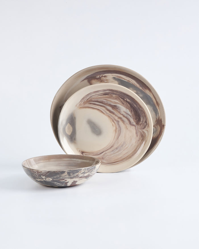 Handmade marbled ceramic dinner set with a bowl and two plates on a light grey background