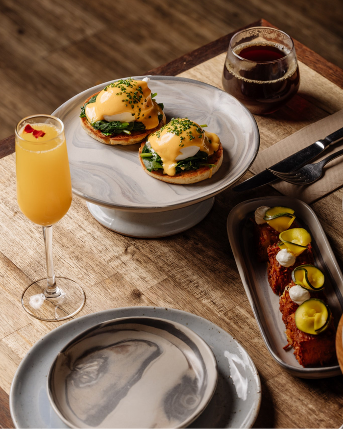 Eggs Benedict served on Palinopsia marble Jupiter ceramics in neutral shades of beige, cream, black, and red.
