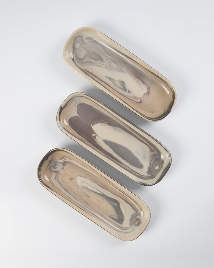 Three marbled clay ceramic oval trays on a white background