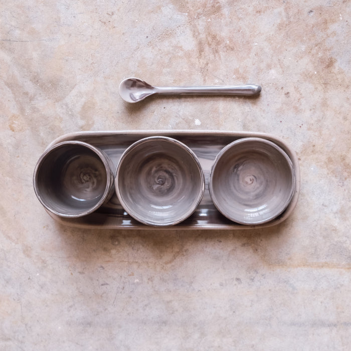 Mezze set of small plates and bowls with a ceramic teaspoon on stone background