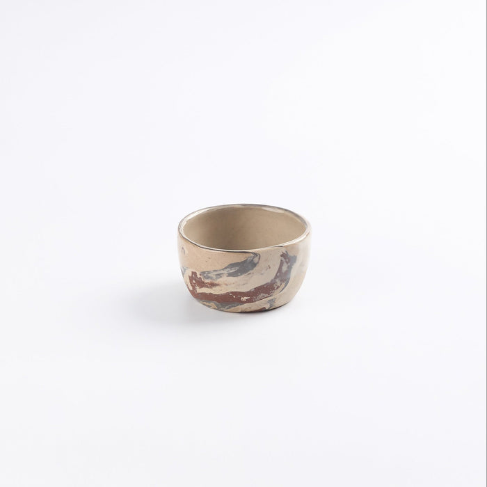 Small marbled ceramic dip bowl in neutral tones against a white background