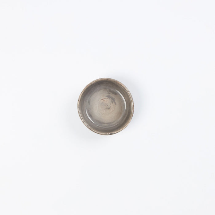 Birds eye view of a small ceramic dish in neutral tones against a white background