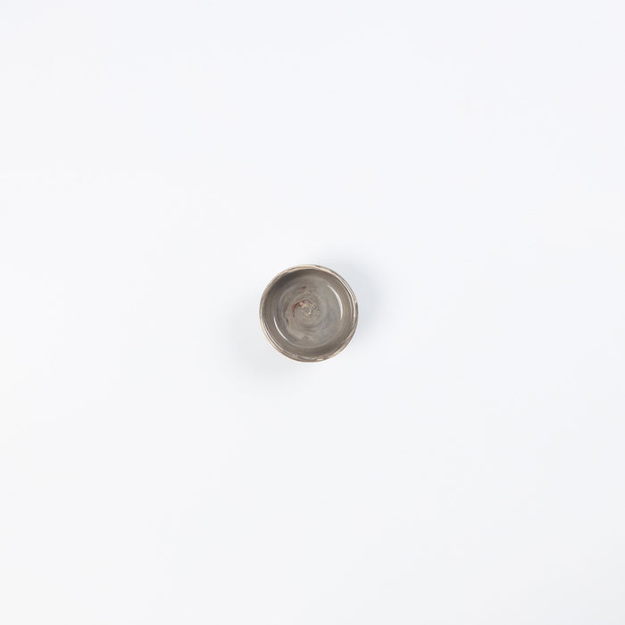 Birds eye view of a small ceramic salt dish in neutral colours on white background