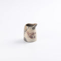 Small ceramic hand pourer pitcher with marbled design on a white background
