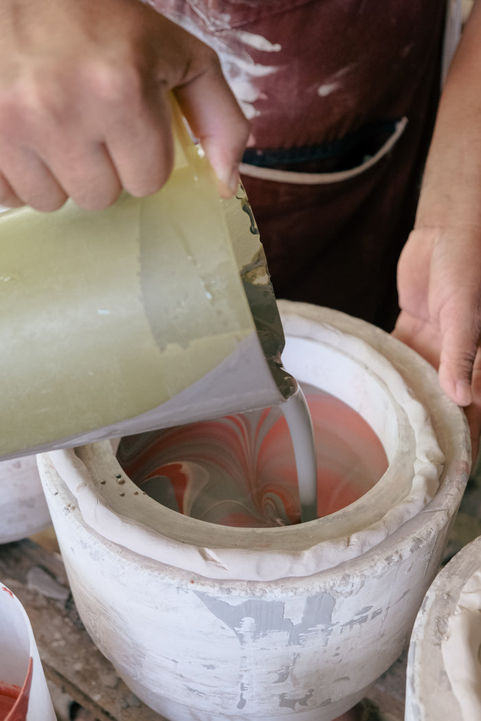 Ceramist pouring liquid slip into a cast to make a hand pitcher