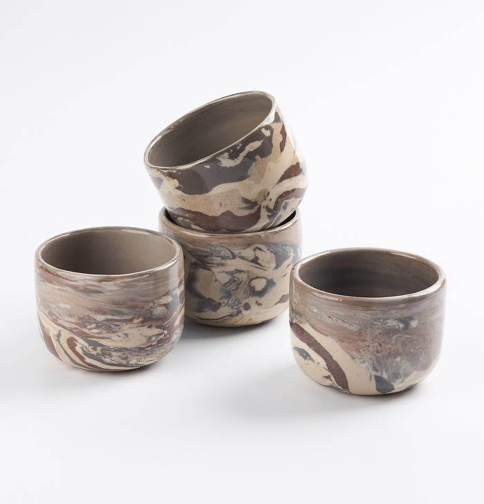 Set of four ceramic cups with four neutral natural clays in a marbled design on a white background by Palinopsia