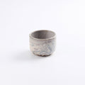 Handmade stoneware coffee cup without a handle, abstract marbled clay design using brown, black, red and natural clay with a pure matte white glaze on a white background.