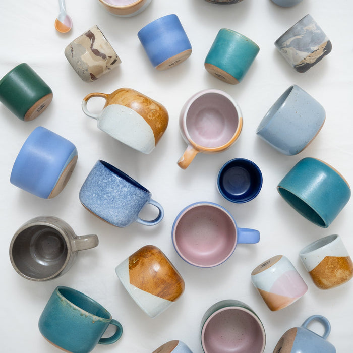 Collection of colorful ceramic mugs and bowls on a white background