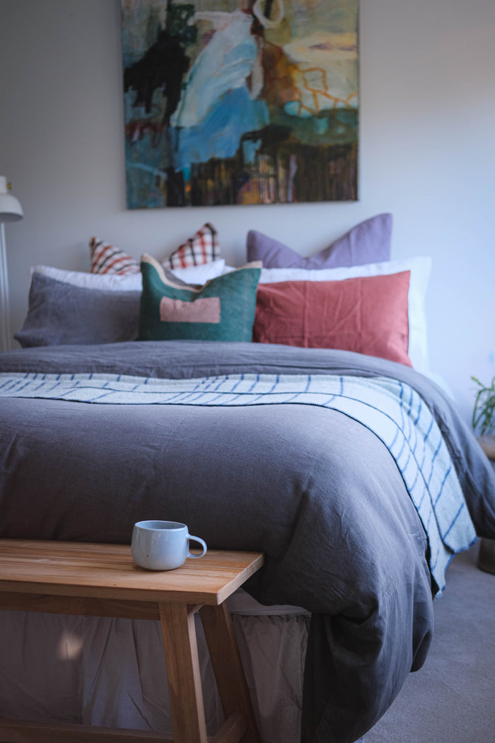 A bedroom setting with a blue handmade coffee mug by Palinopsia