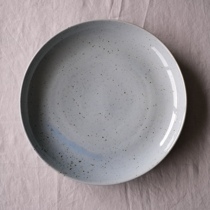 Large round serving platter by Palinopsia Ceramics in a blue and grey speckle handmade stoneware. Birdseye view on a grey tablecloth