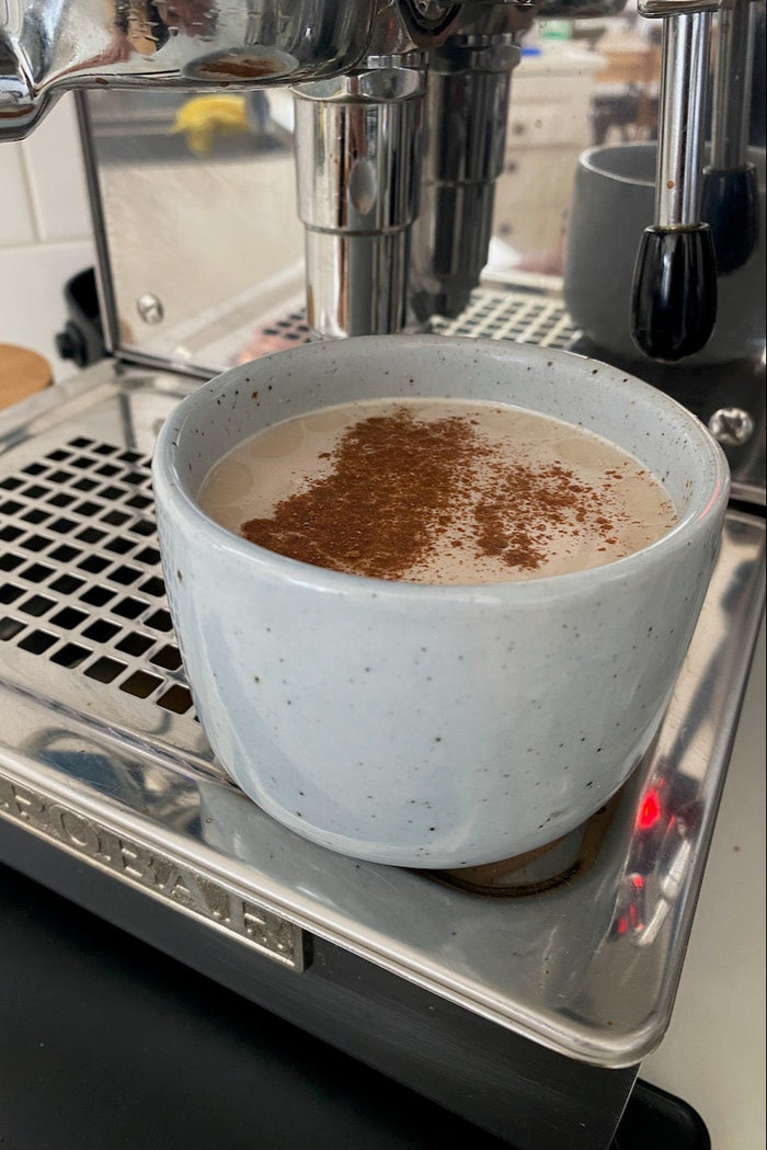 A blue coffee cup placed on a  coffee machine  at Palinopsia Ceramics