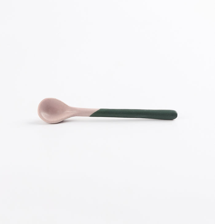 Ceramic spoon with a green handle and pink tip on a white background