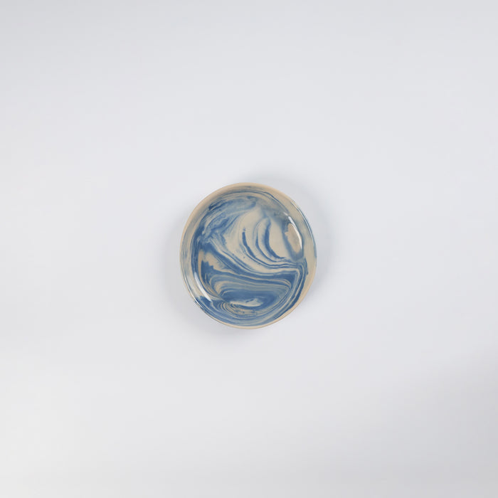 Small handmade ceramic plate with a marbled clay pattern in cobalt blue, beige and cream on a white background by Palinopsia