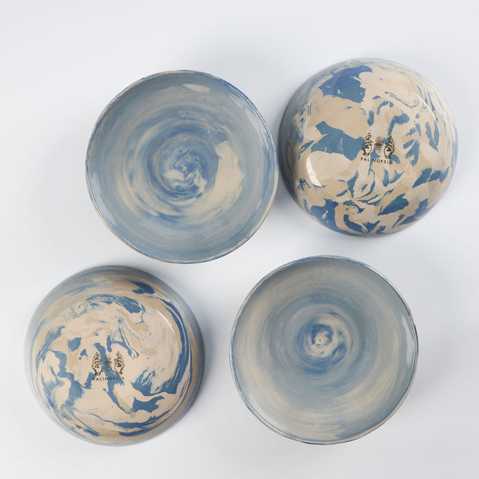 Set of four handmade ceramic bowls with a marbled clay pattern in cobalt blue, beige and cream on a white background by Palinopsia