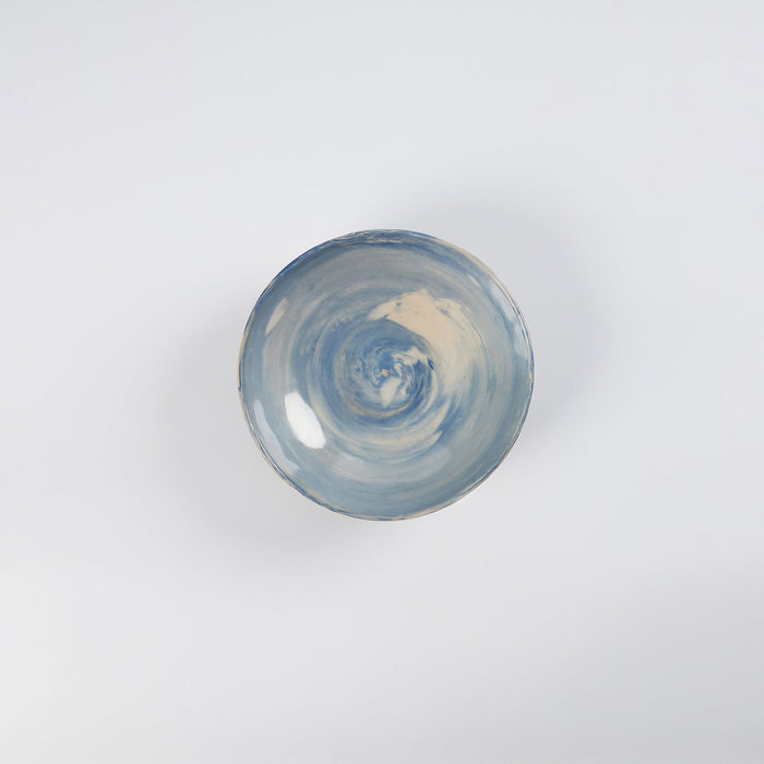 Handmade ceramic bowl with a marbled clay pattern in cobalt blue, beige and cream on a white background by Palinopsia