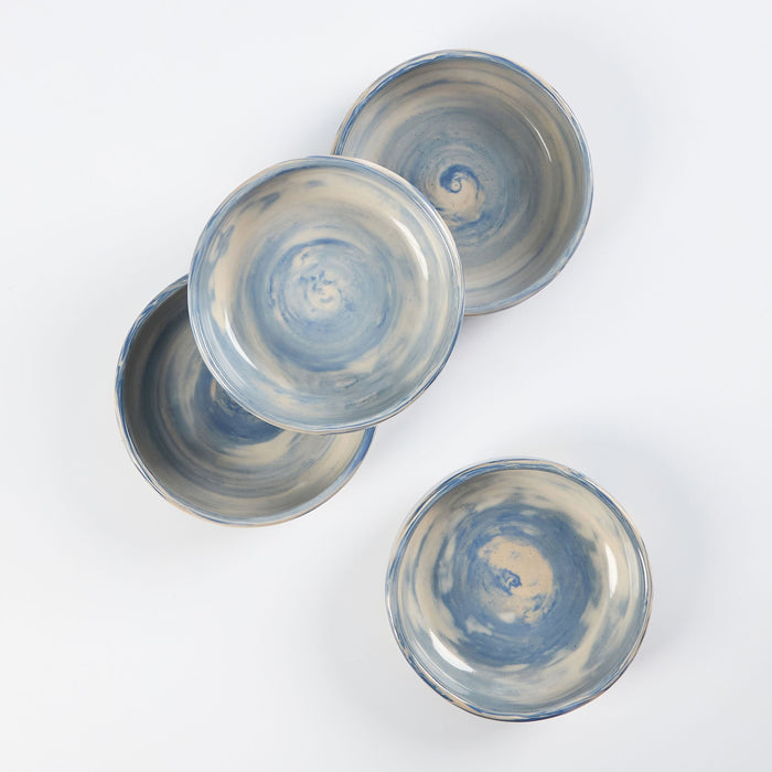 Set of four handmade ceramic bowls with a marbled clay pattern in cobalt blue, beige and cream on a white background by Palinopsia