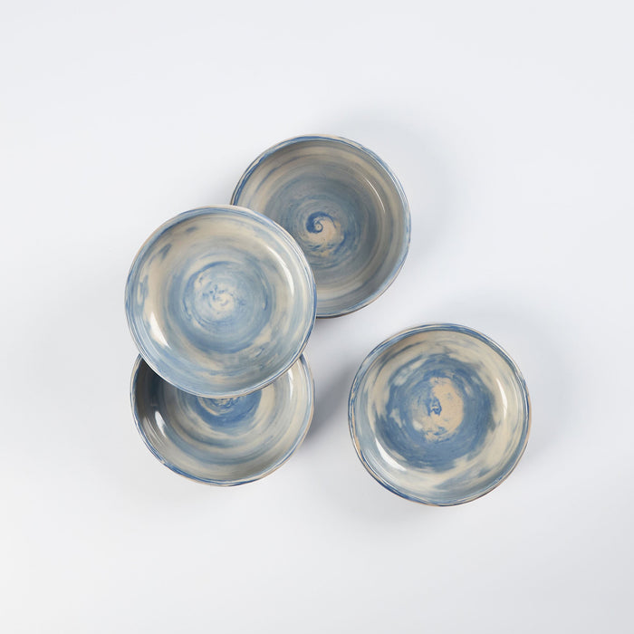 Set of four handmade ceramic bowls with a marbled clay pattern in cobalt blue, beige and cream on a white background by Palinopsia