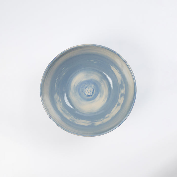 Handmade ceramic bowl with a swirling marbled clay pattern in cobalt blue, beige and cream on a white background by Palinopsia