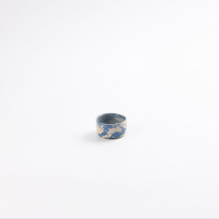 Small handmade ceramic salt pinch with a swirling marbled clay pattern in cobalt blue, beige and cream on a white background by Palinopsia
