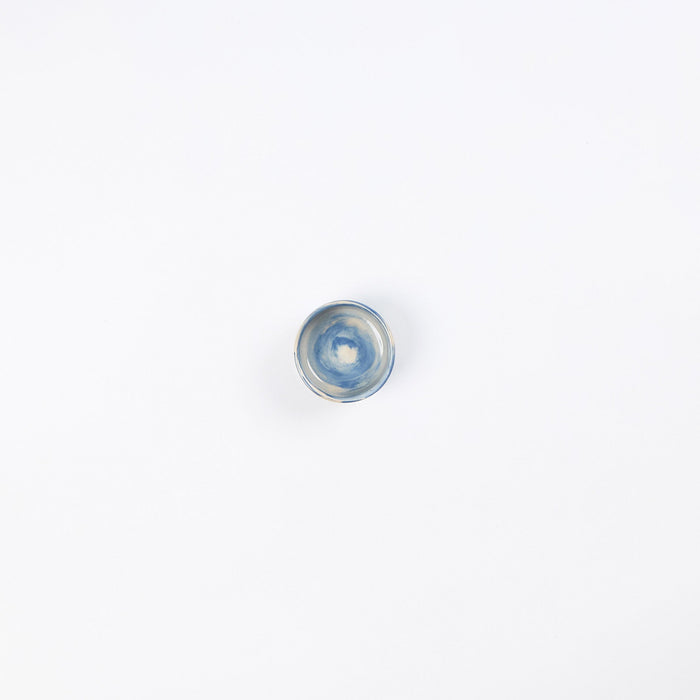 Small handmade ceramic salt pinch with a swirling marbled clay pattern in cobalt blue, beige and cream on a white background by Palinopsia