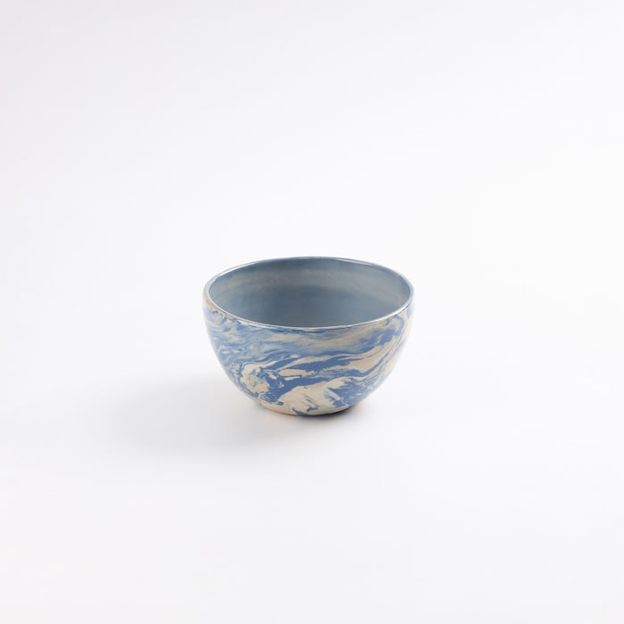 Small handmade ceramic bowl with a swirling marbled clay pattern in cobalt blue, beige and cream on a white background by Palinopsia