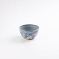 Small handmade ceramic bowl with a swirling marbled clay pattern in cobalt blue, beige and cream on a white background by Palinopsia