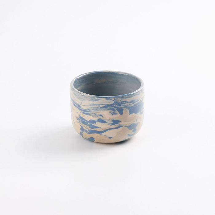 Tumbler ceramic cup with a blue and white marbled pattern on a white background