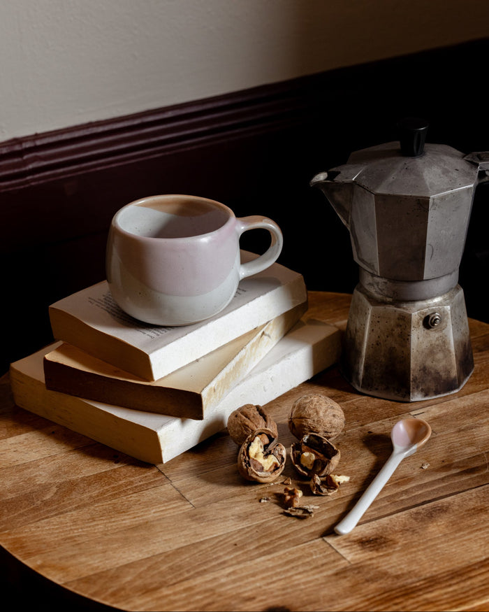 Ceramic mug and teaspoon with a Bialetti Moka styled on reading books