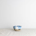 Handmade blue and white little breakfast bowl with splatter design on a white tablecloth by Palinopsia Ceramics