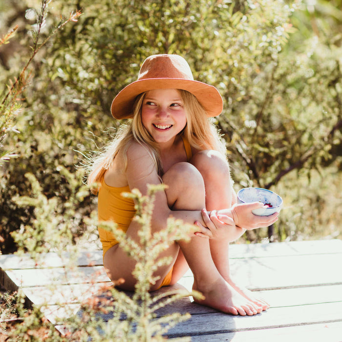 Girl holds a little ceramic bowl in blue and white filled with summer fruit by Palinopsia Ceramics