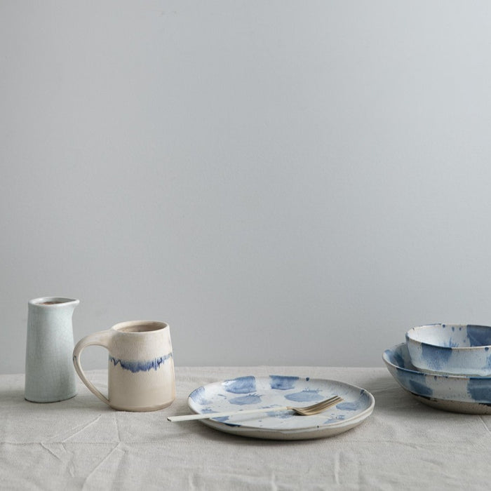 Blue and white ceramics and pottery on a white linen tablecloth by Palinopsia