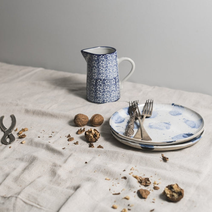 Lunch plates stacked with walnuts, and a handmade blue and white  jug