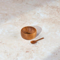 Small Palinopsia wooden teak salt bowl with matching spoon on a stone bench top