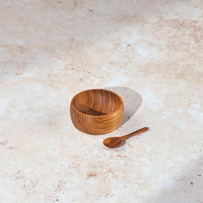 Small Palinopsia wooden teak salt bowl with matching spoon on a stone bench top