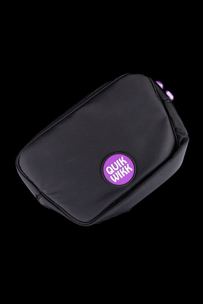 Diagonal close-up of a black Quik Wikk Chest Pack showing a purple circular logo and two purple zipper tabs against a black background
