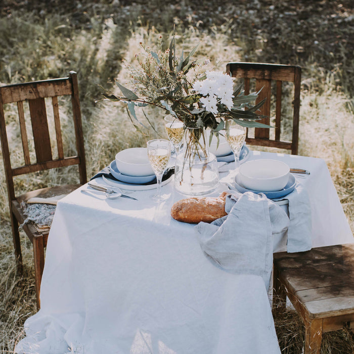 Australian outdoor dining with native flowers and Palinopsia handmade dinner set in white and blue on a white table cloth in Sydney
