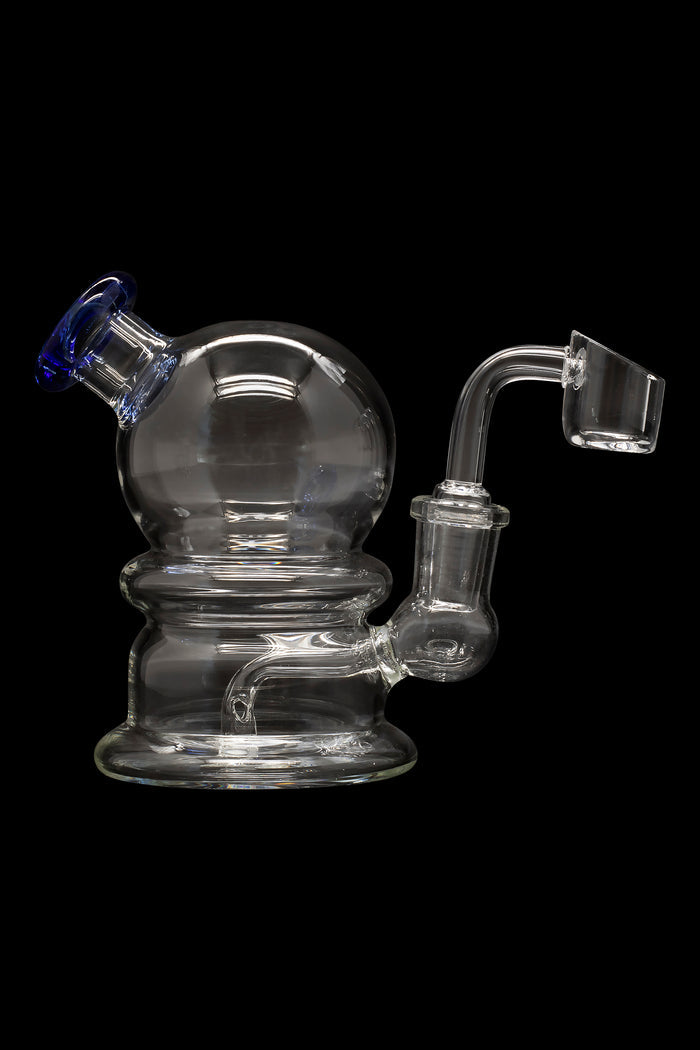 Clear glass dab rig with a spherical body and quartz banger, isolated on a black background.
